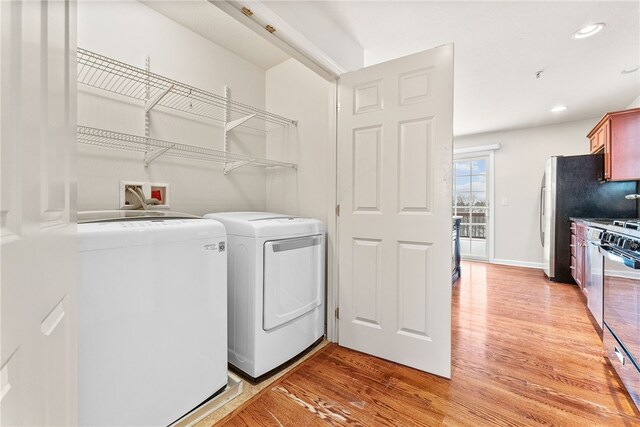 laundry room with washer and clothes dryer and light hardwood / wood-style flooring