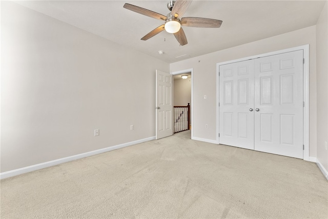 unfurnished bedroom featuring light carpet, a closet, and ceiling fan