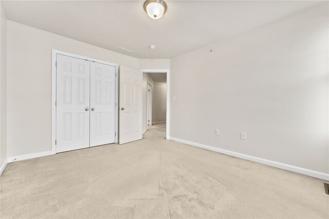 unfurnished bedroom featuring light carpet and a closet