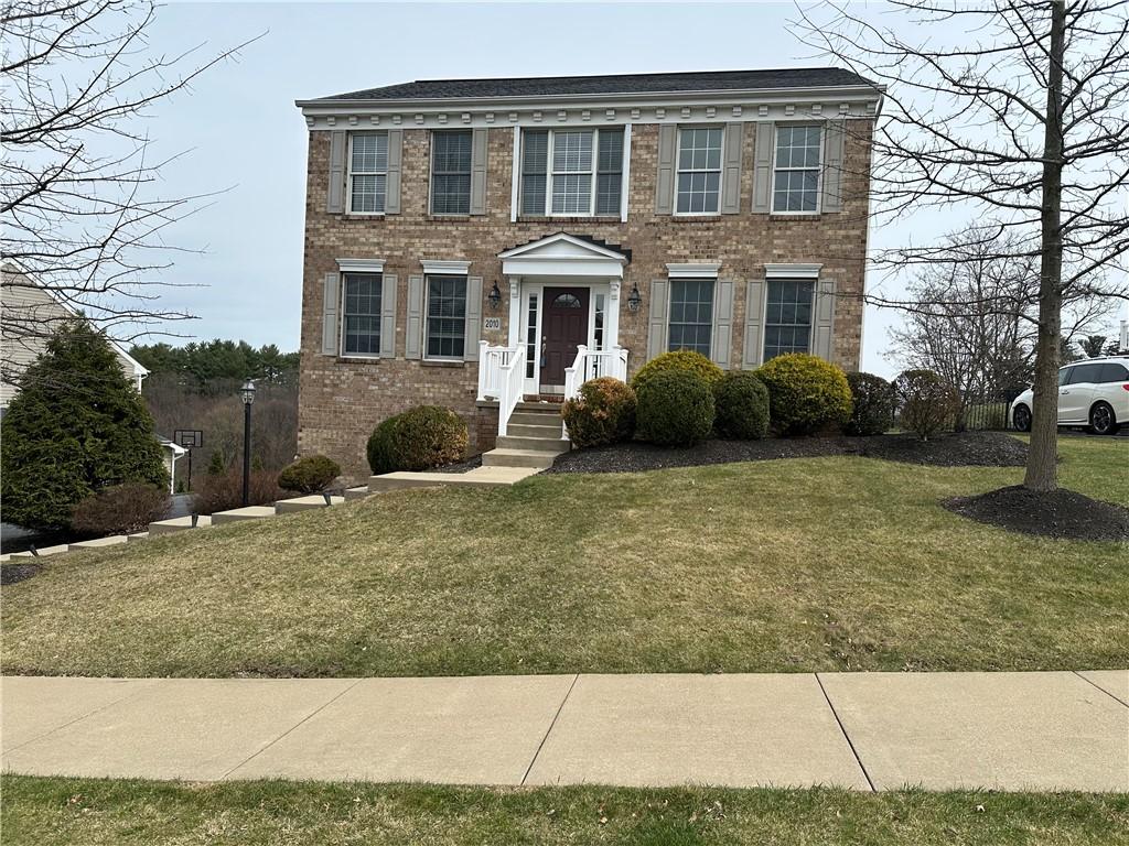 colonial house with brick siding and a front lawn