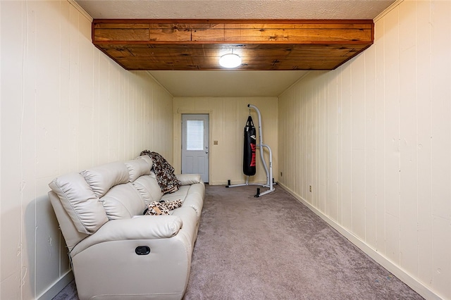 sitting room featuring wood walls, beam ceiling, and light carpet