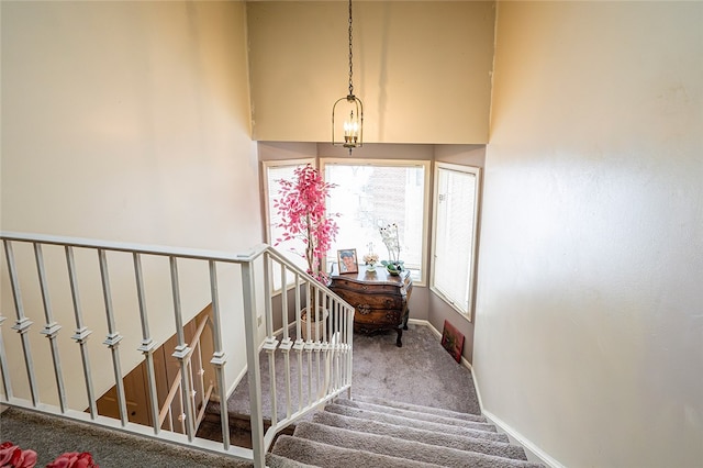 stairway featuring carpet floors and an inviting chandelier