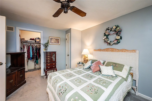 carpeted bedroom featuring a walk in closet, ceiling fan, and a closet