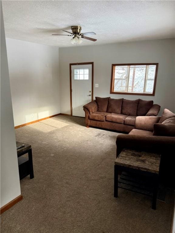 living room with ceiling fan, carpet floors, and a textured ceiling