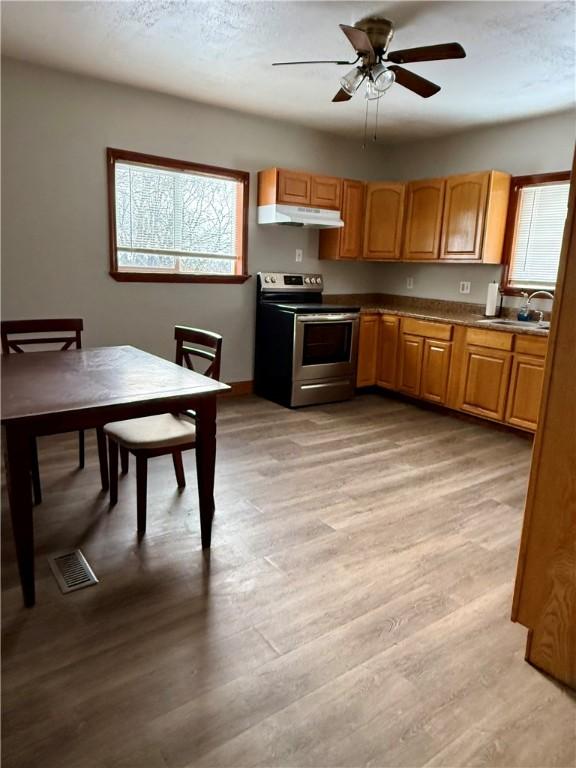 kitchen with light wood-type flooring, electric range, ceiling fan, and sink