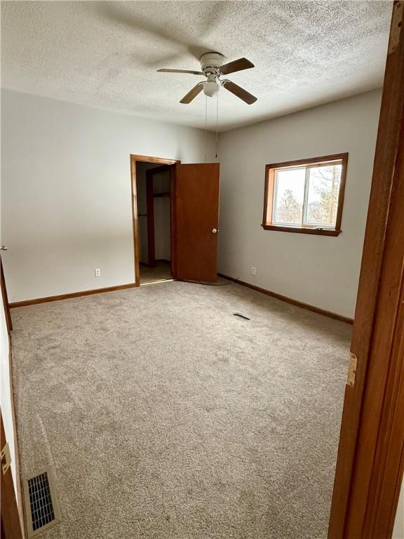 unfurnished bedroom with a textured ceiling, carpet floors, and ceiling fan