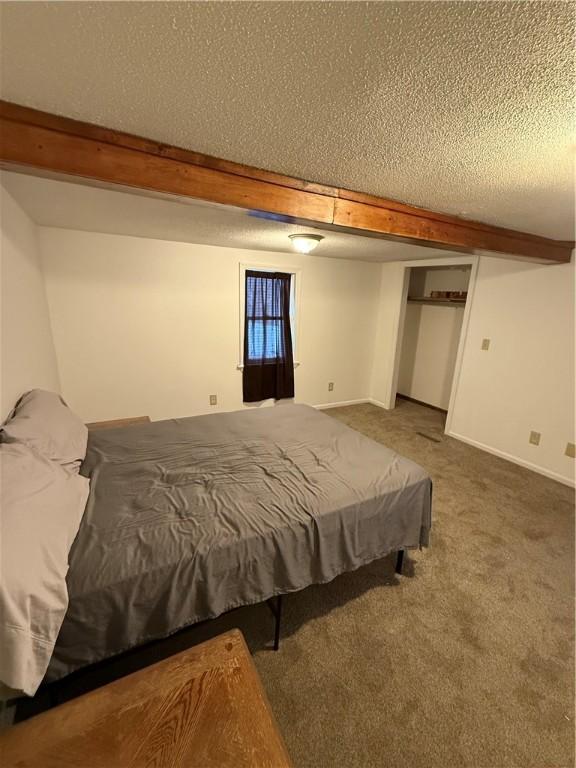 bedroom featuring carpet flooring, beamed ceiling, and a textured ceiling