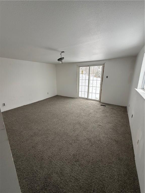 carpeted empty room with a textured ceiling