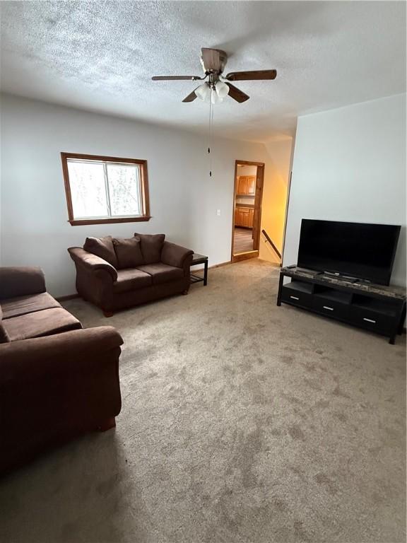 carpeted living room featuring a textured ceiling and a ceiling fan