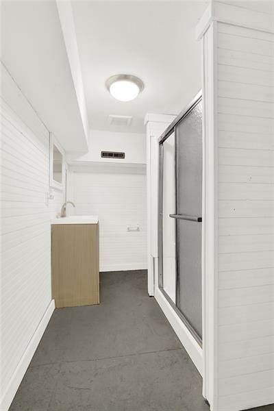 bathroom with concrete flooring, vanity, and a shower with shower door