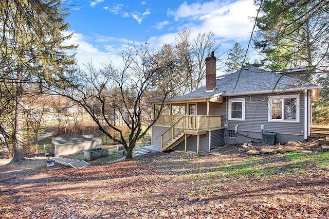 rear view of house with central AC unit and a storage shed