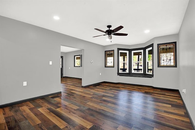 empty room featuring a wealth of natural light, dark wood-type flooring, and ceiling fan