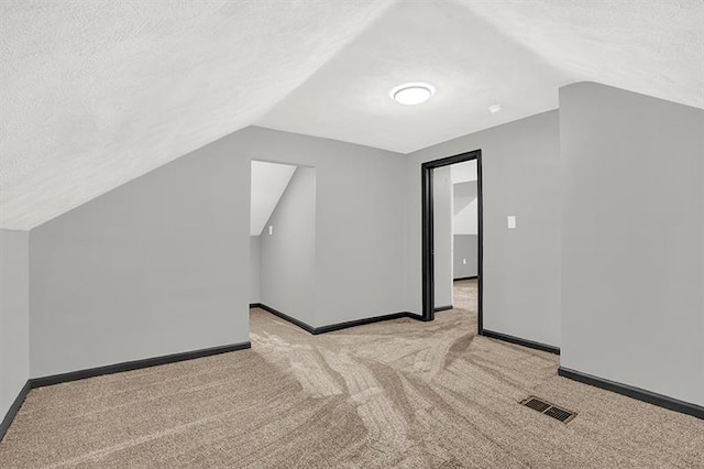 bonus room featuring a textured ceiling, light carpet, and vaulted ceiling