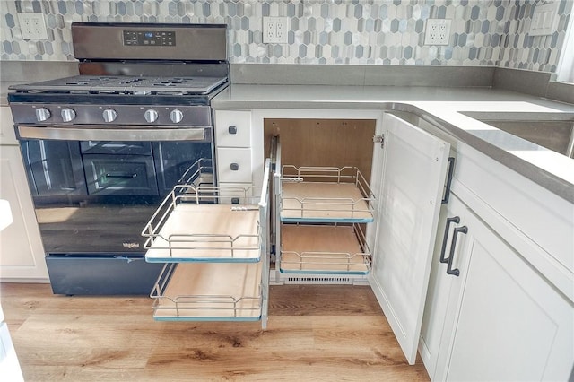 kitchen with range with gas stovetop, light wood-type flooring, and white cabinetry