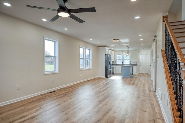 unfurnished living room with ceiling fan and light wood-type flooring