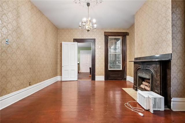 unfurnished living room with a multi sided fireplace, dark hardwood / wood-style floors, and an inviting chandelier