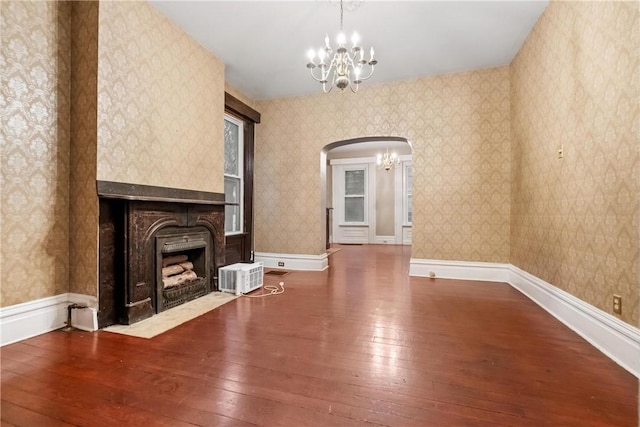 unfurnished living room featuring wood-type flooring and an inviting chandelier