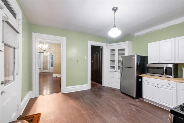 kitchen with hanging light fixtures, white cabinets, stainless steel appliances, and dark hardwood / wood-style floors