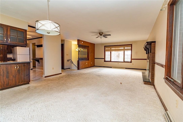 unfurnished living room featuring baseboard heating, light carpet, and ceiling fan