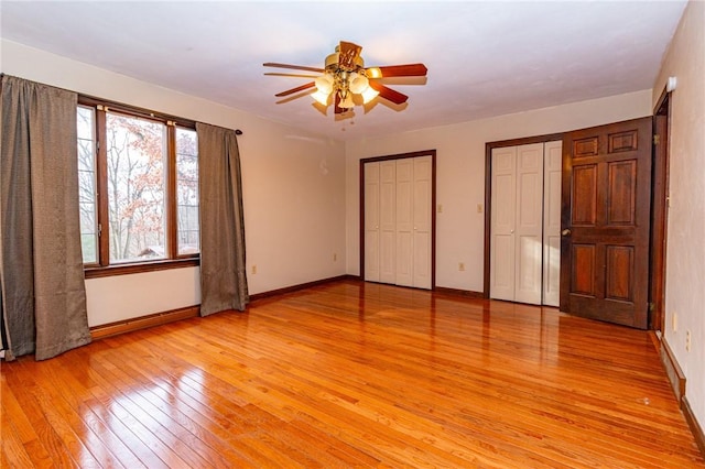 unfurnished bedroom with ceiling fan, multiple closets, multiple windows, and light hardwood / wood-style flooring