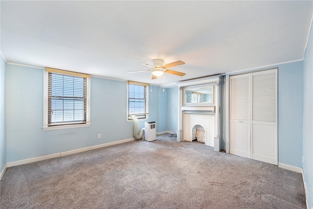 unfurnished bedroom featuring carpet, ceiling fan, crown molding, and two closets