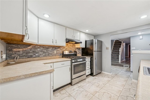 kitchen with backsplash, white cabinets, and stainless steel appliances