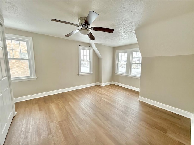 bonus room featuring ceiling fan, light hardwood / wood-style flooring, and a textured ceiling