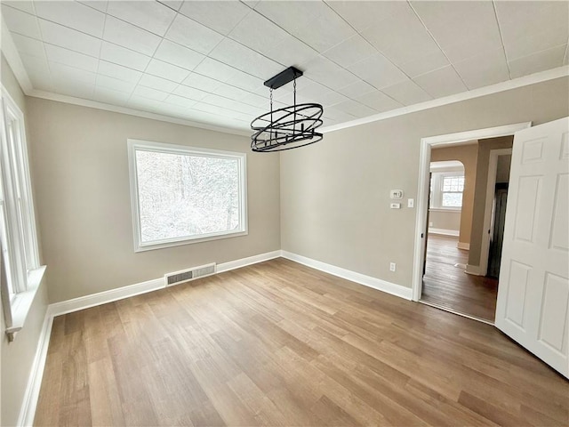 unfurnished dining area featuring hardwood / wood-style flooring, a chandelier, and ornamental molding