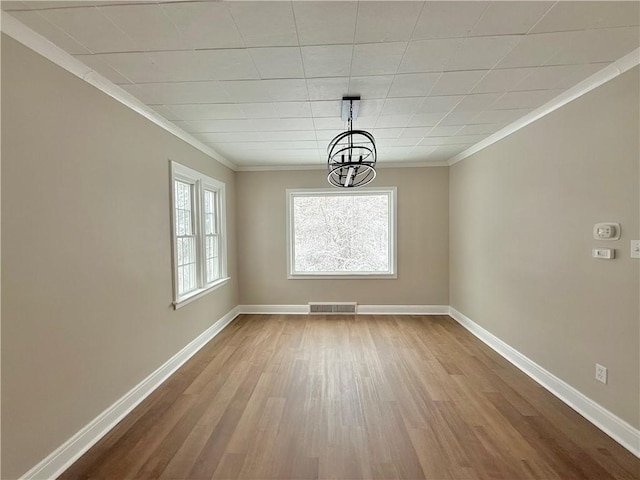 unfurnished dining area with hardwood / wood-style floors, an inviting chandelier, and crown molding