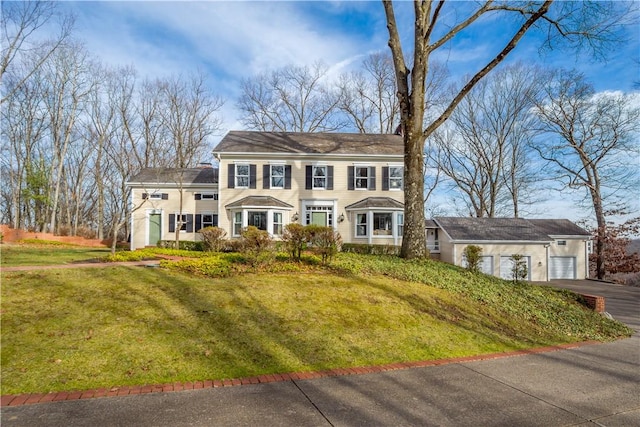 colonial house featuring a front yard and a garage