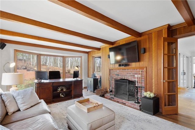 living room featuring beam ceiling, wood walls, and a fireplace