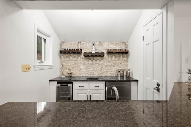 bar featuring refrigerator, dark stone counters, white cabinetry, wine cooler, and lofted ceiling