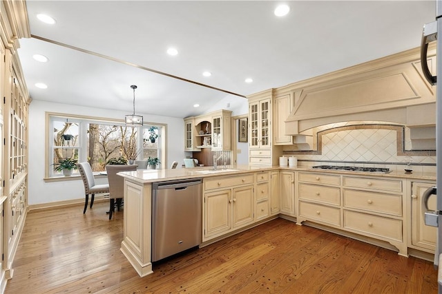 kitchen with hanging light fixtures, light hardwood / wood-style floors, cream cabinetry, decorative backsplash, and appliances with stainless steel finishes