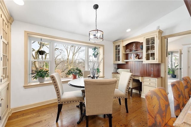 dining space featuring a notable chandelier, vaulted ceiling, and light wood-type flooring