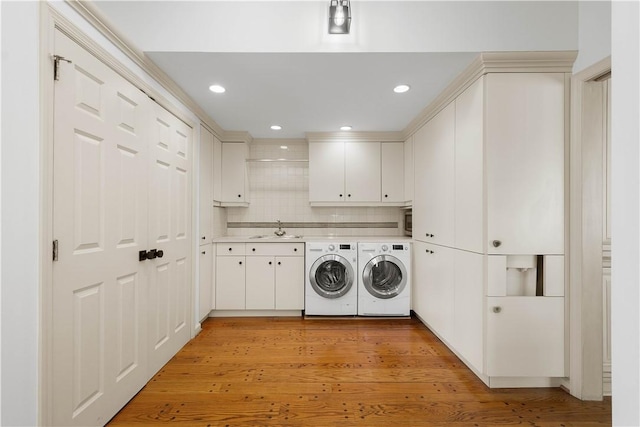 laundry area with washing machine and dryer, sink, cabinets, and light hardwood / wood-style flooring