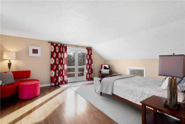 bedroom with wood-type flooring, a textured ceiling, and vaulted ceiling