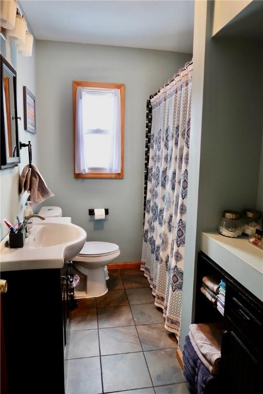 bathroom with tile patterned floors, vanity, toilet, and walk in shower