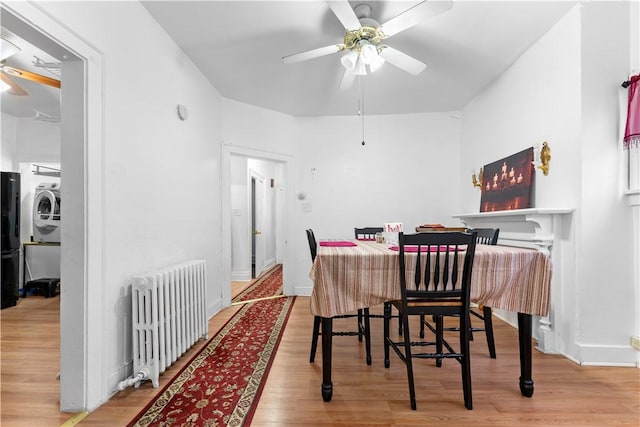 dining room with ceiling fan, light wood-type flooring, radiator heating unit, and washer / clothes dryer