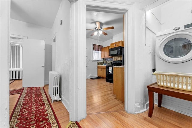 hallway with washer / dryer, radiator heating unit, and light hardwood / wood-style flooring