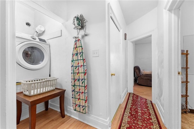 clothes washing area with washer / clothes dryer and light wood-type flooring