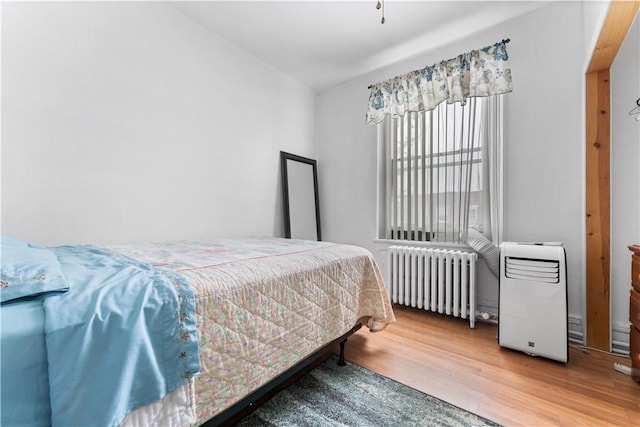 bedroom with radiator heating unit and wood-type flooring