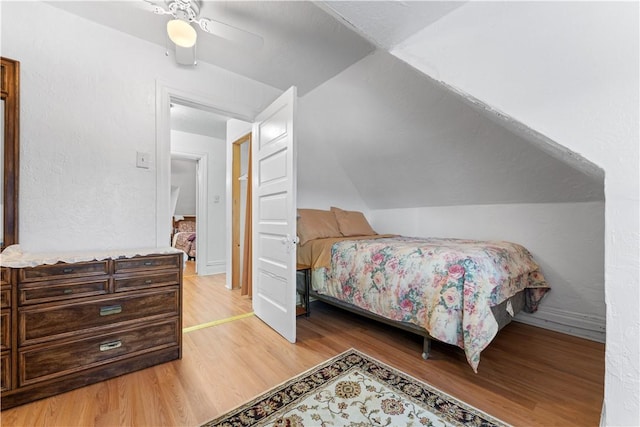 bedroom with ceiling fan, light hardwood / wood-style floors, and vaulted ceiling