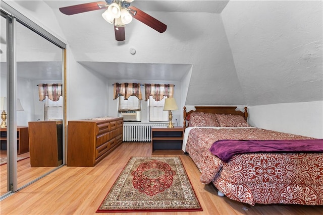 bedroom featuring vaulted ceiling, ceiling fan, hardwood / wood-style flooring, radiator heating unit, and a closet