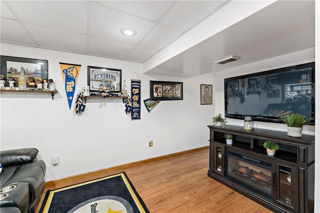 living room featuring a paneled ceiling and hardwood / wood-style flooring