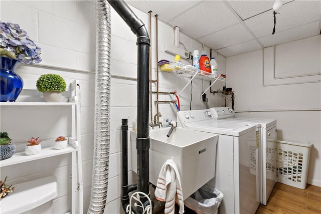 washroom with light hardwood / wood-style floors, separate washer and dryer, and sink