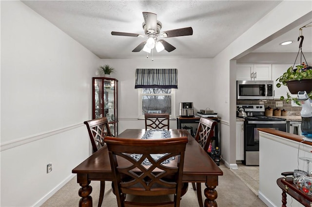 dining room with ceiling fan, light carpet, and a textured ceiling