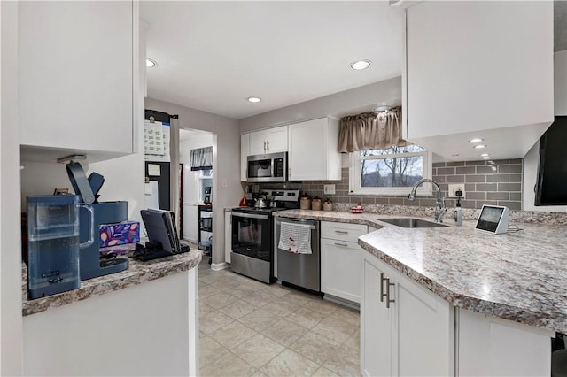 kitchen featuring decorative backsplash, sink, white cabinets, and appliances with stainless steel finishes