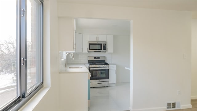 kitchen with white cabinets, decorative backsplash, stainless steel appliances, and sink