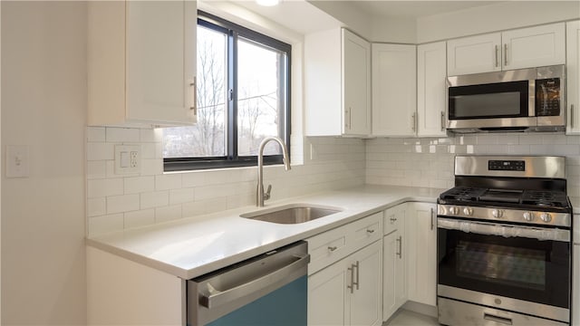 kitchen featuring tasteful backsplash, sink, white cabinets, and appliances with stainless steel finishes