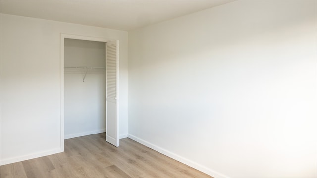 unfurnished bedroom with light wood-type flooring and a closet